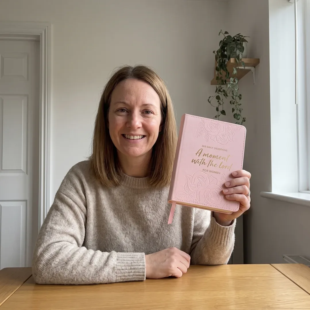 A woman holding A Moment With the Lord at home